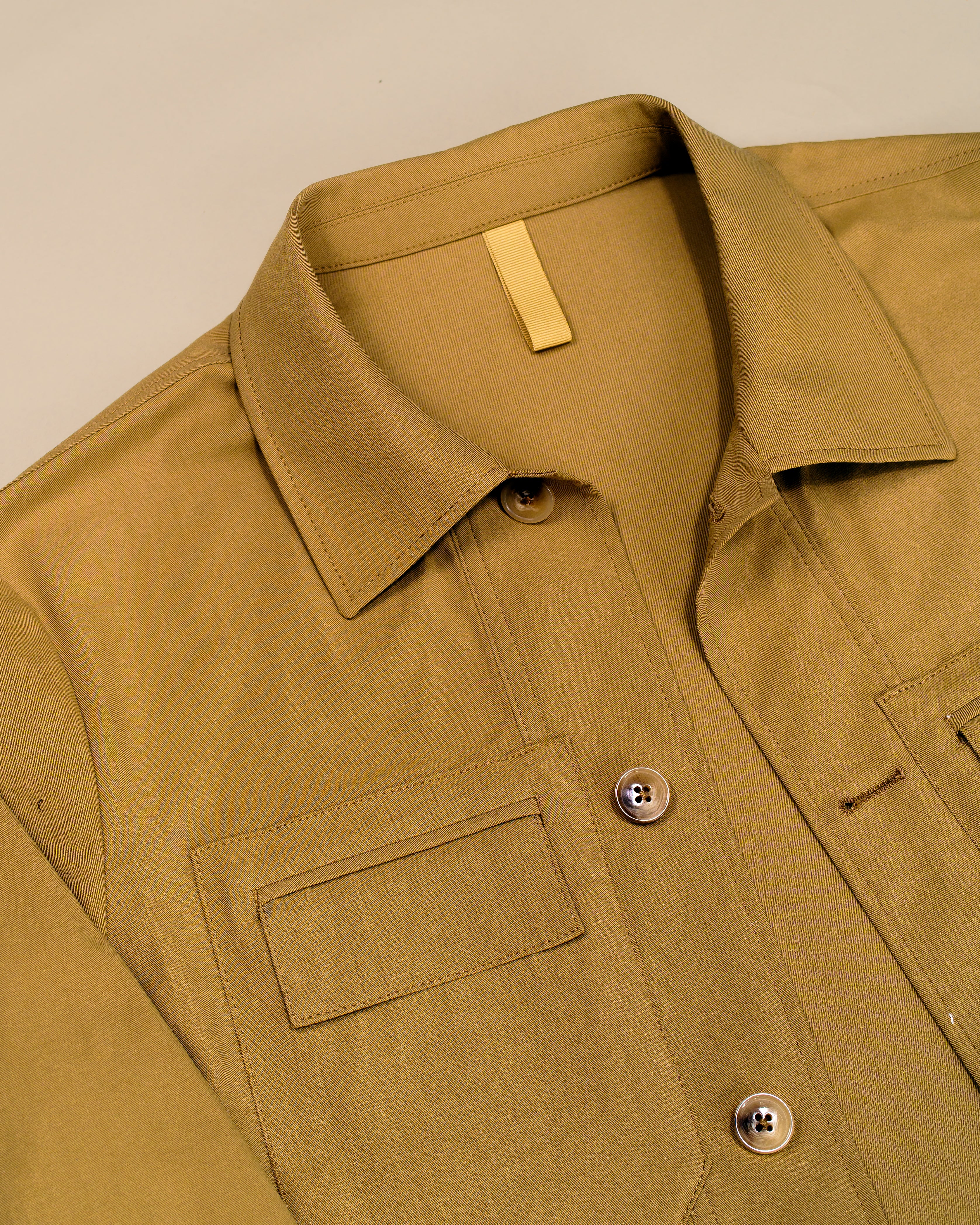 Close-up of the WJ-001 work jacket in tan, highlighting the collar, button placket, and chest pocket stitching.