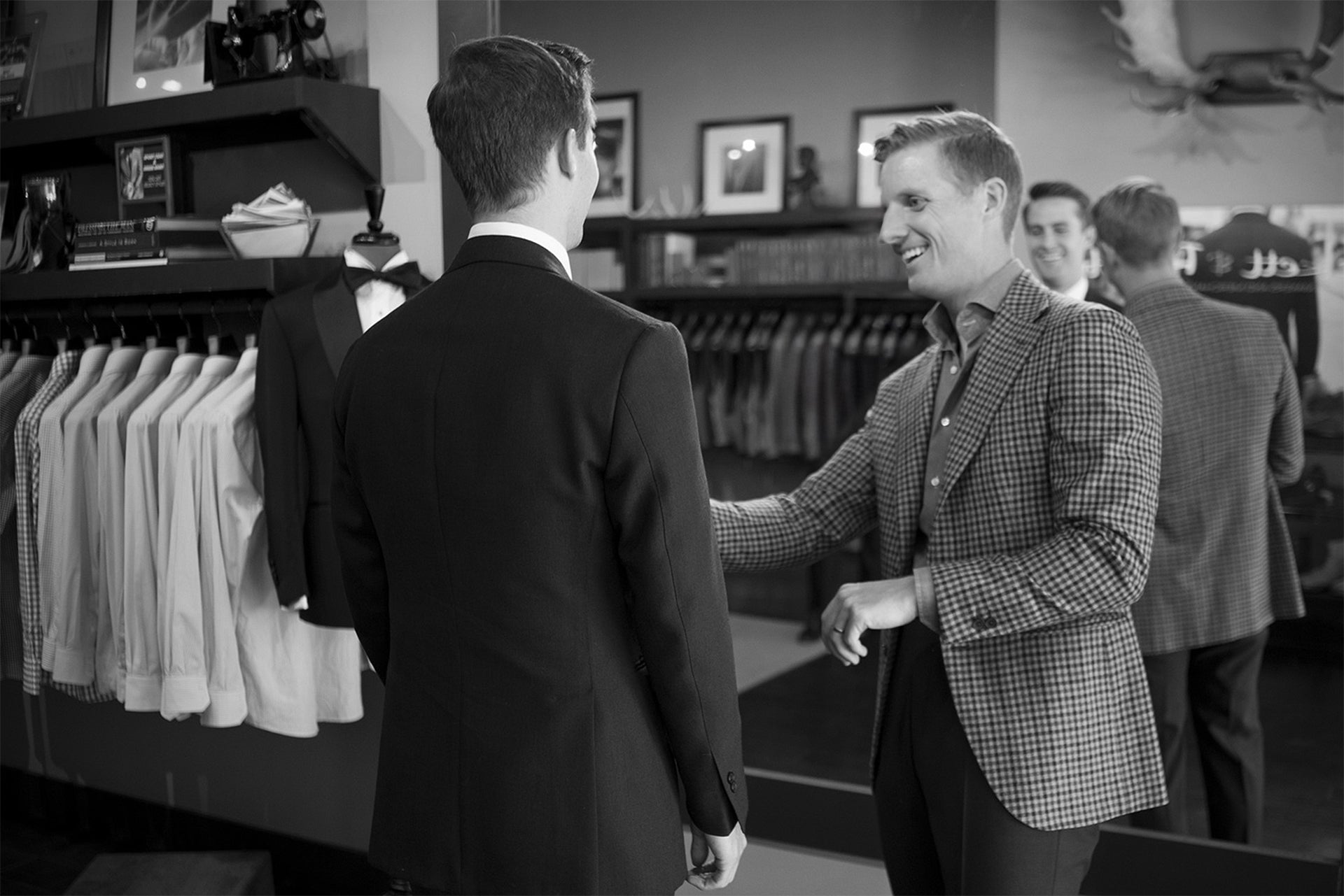 Beckett & Robb tailor assisting a client during a suit fitting in-store, surrounded by shirts, jackets, and mirrors.
